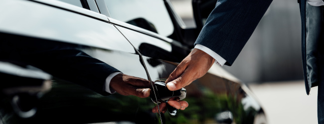 Abbildung: Geschäftsmann öffnet Firmenwagen - Firmenwagenbesteuerung