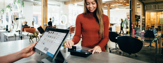 Abbildung: junge Frau bei Kartenzahlung an einer elektronischen Kasse
