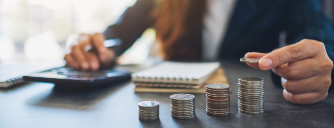 Abbildung: Geschäftsfrau, die Münzen hält und stapelt, während sie Geld auf dem Tisch berechnet